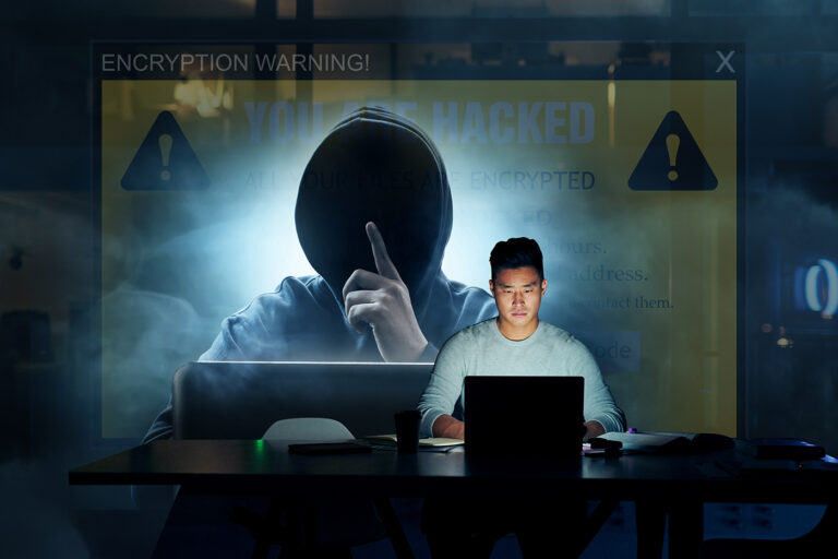 Cybersecurity concept image showing a ransomware attack, with a user's files being encrypted by a hooded hacker figure displayed on a large warning screen.