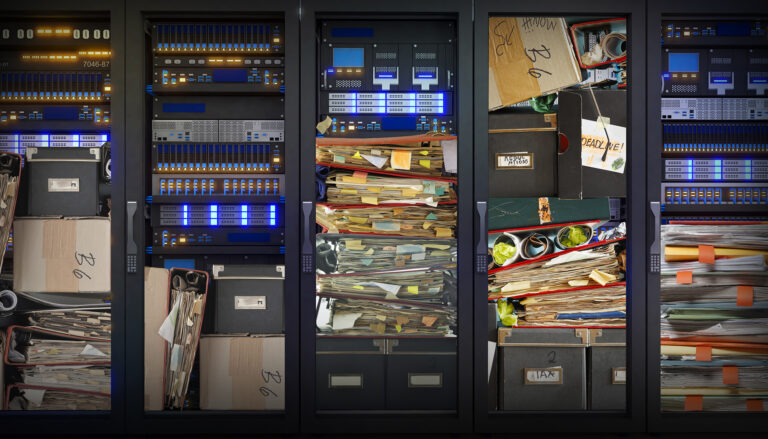 Server racks beside overflowing filing cabinets and boxes labeled "tax," "regulations," and "deadline," symbolizing outdated, redundant digital data.